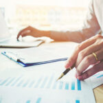 Business man holding pen pointing on summary report chart