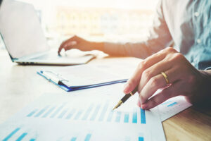 Business man holding pen pointing on summary report chart