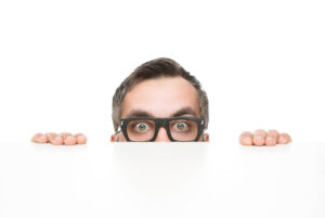 Guy peeking over the edge of a white desk
