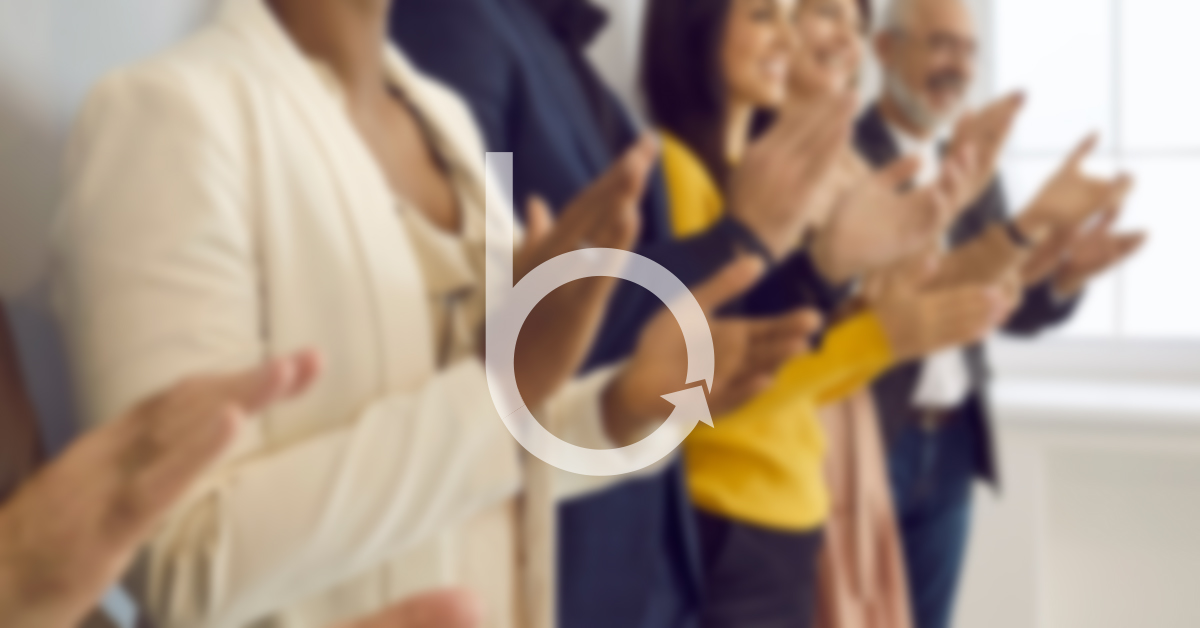 People applauding behind a blurred background with the Buckingham "b" in front.